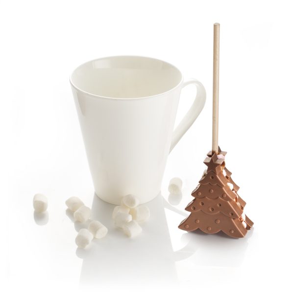 Christmas tree hot chocolate stirrer next to a mug