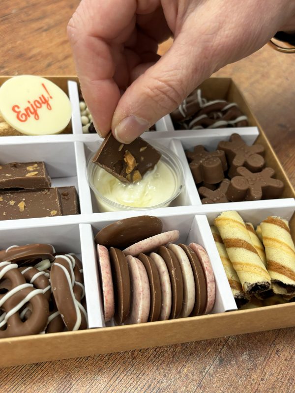 Chocolate grazing box being dipped into with a piece of chocolate